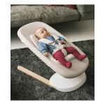 Bebé recostado y sujeto con arnés en la hamaca Yoga de Stokke sobre alfombra oscura.