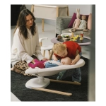 Mamá y niño pequeño acariciando a un bebé recostado en la hamaca Yoga de Stokke.
