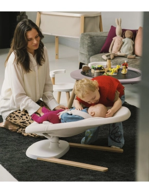 Mamá y niño pequeño acariciando a un bebé recostado en la hamaca Yoga de Stokke.