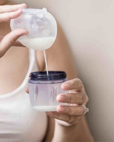 Mujer vaciando un recolectorLadybug 40ml de Haakaa en un vaso de biberón