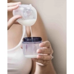 Mujer vaciando un recolectorLadybug 40ml de Haakaa en un vaso de biberón