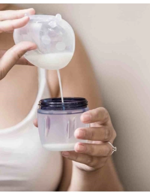 Mujer vaciando un recolectorLadybug 40ml de Haakaa en un vaso de biberón