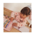 Niña pintando con el Babi con botones Little Red de Tutete